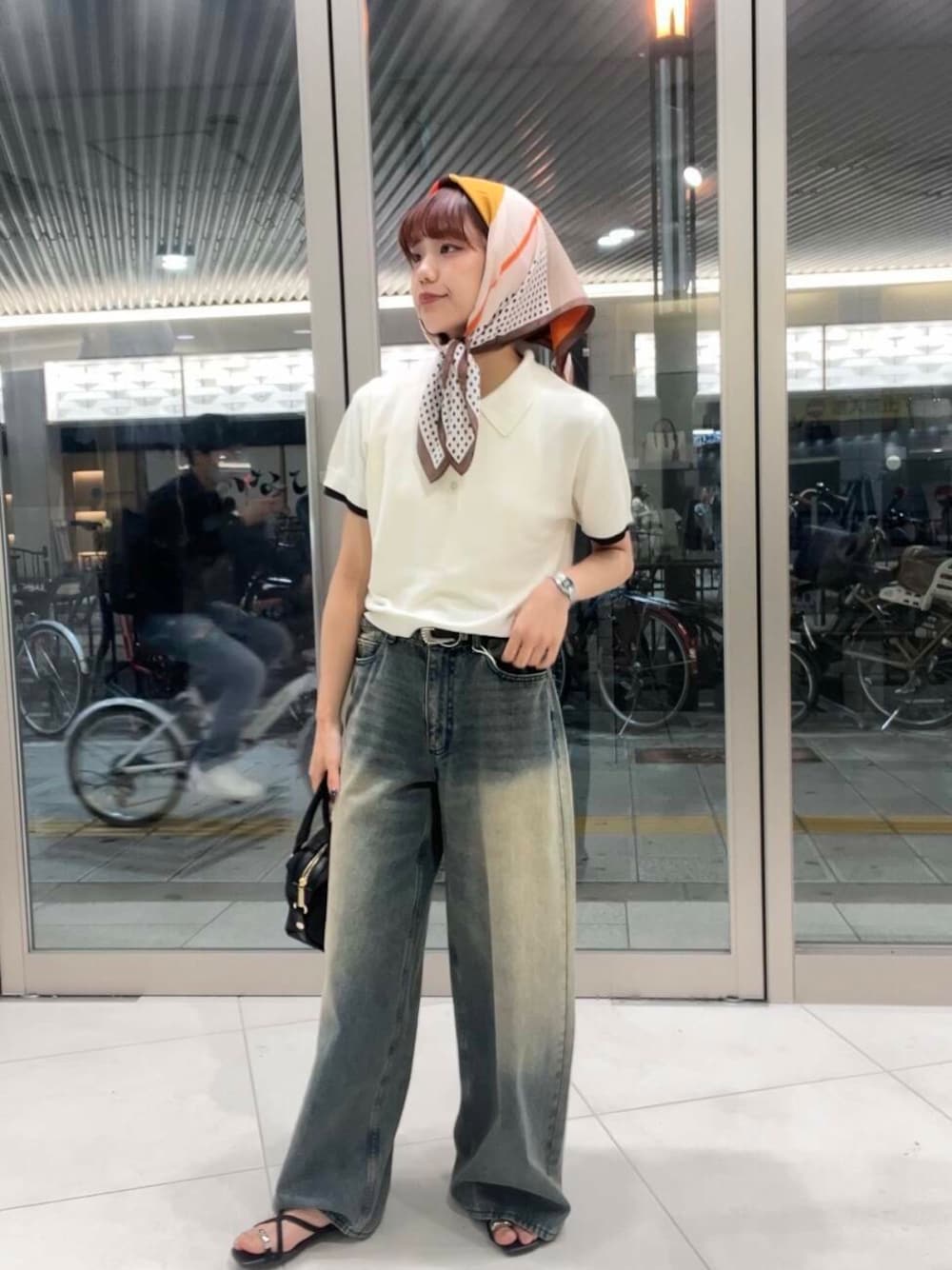 ブルー系のデニムパンツ、ブラック系のサンダル、ホワイト系のポロシャツを着用したレディースの夏コーディネートの1枚目の写真