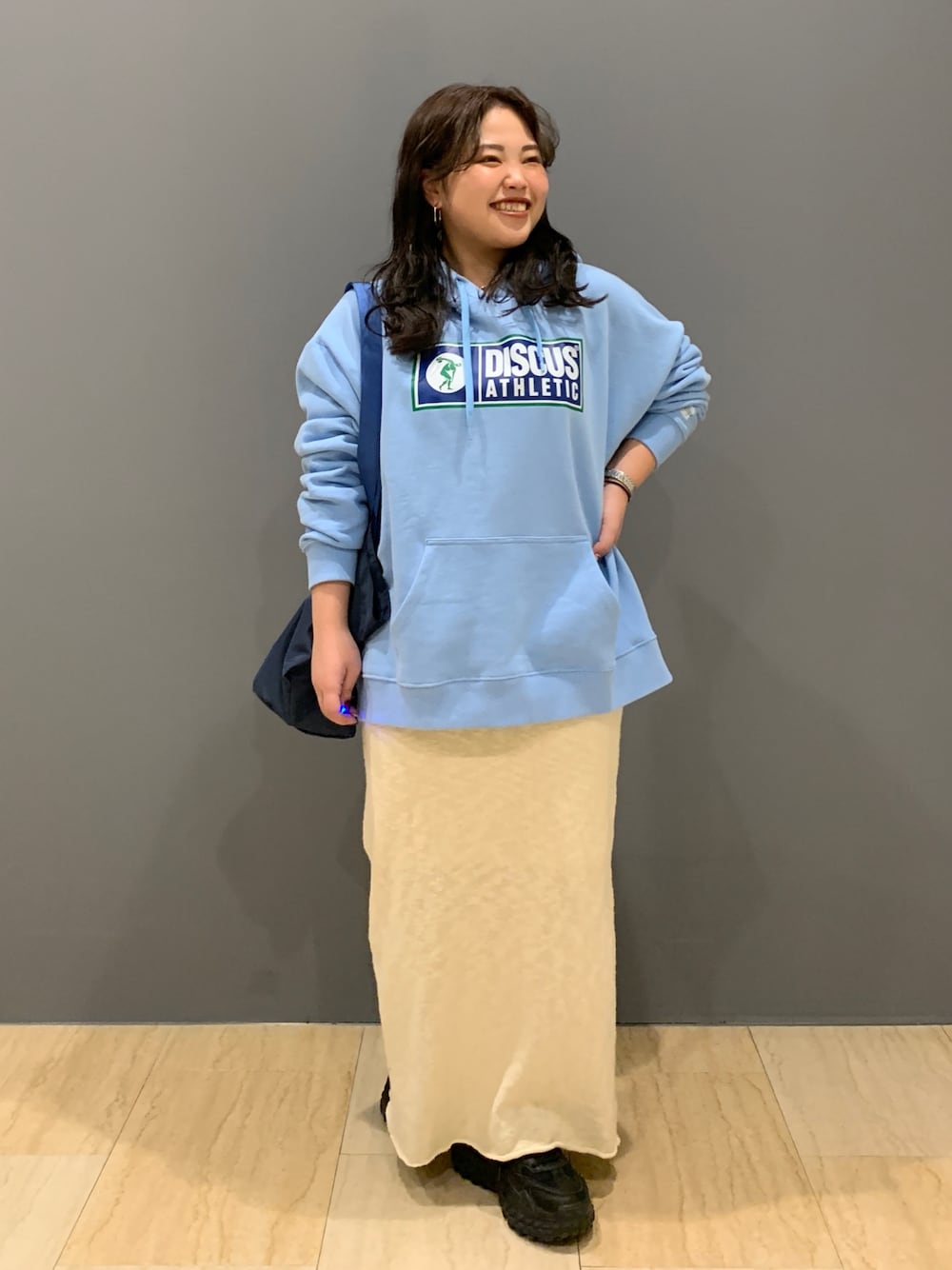 ブルー系のパーカー、ホワイト系のスカート、ブルー系のトートバッグを着用したレディースの冬コーディネートの1枚目の写真