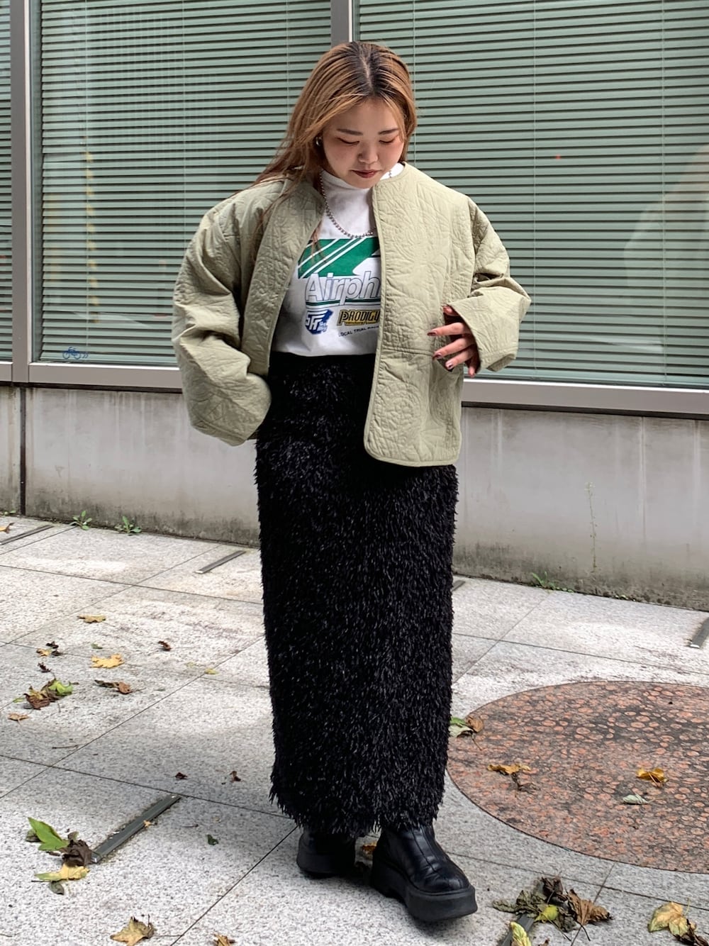 グリーン系のブルゾン、ホワイト系のTシャツ/カットソー、ブラック系のスカートを着用したレディースの秋コーディネートの1枚目の写真