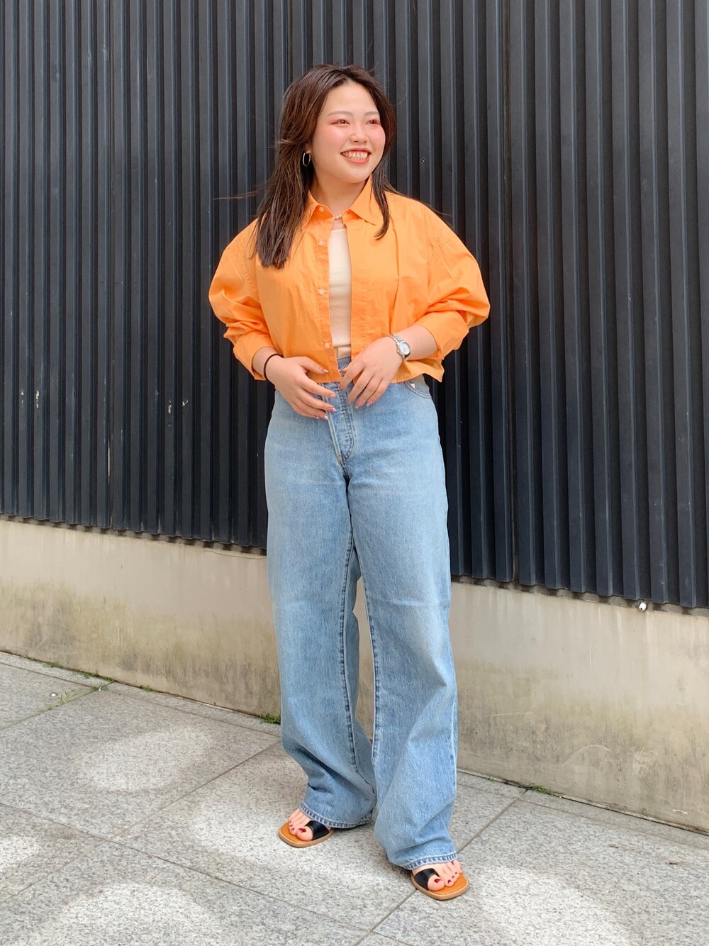 オレンジ系のシャツ/ブラウス、ホワイト系のキャミソール、ブルー系のデニムパンツを着用したレディースの春コーディネートの1枚目の写真