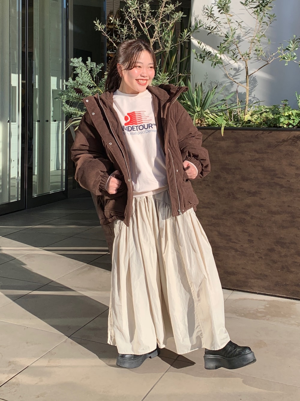 ホワイト系のスウェット、ブラウン系のブルゾン、ホワイト系のスカートを着用したレディースの冬コーディネートの1枚目の写真