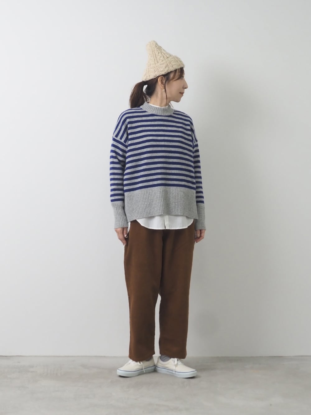 グレー系のニット/セーター、ブラウン系のパンツを着用したレディースの秋コーディネートの1枚目の写真