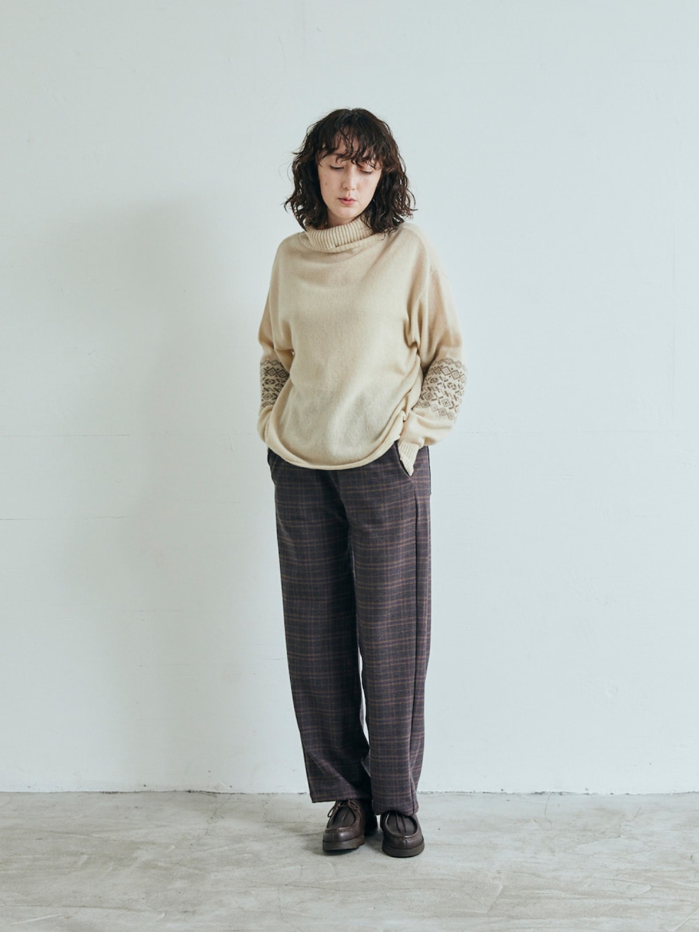 ベージュ系のニット/セーター、ブラウン系のスラックスを着用したレディースの秋コーディネートの1枚目の写真