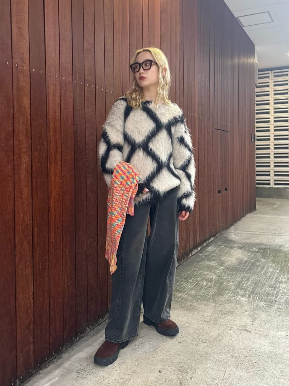 ホワイト系のニット/セーター、ブラック系のデニムパンツ、ブラウン系のブーツを着用したレディースの秋コーディネートの1枚目の写真