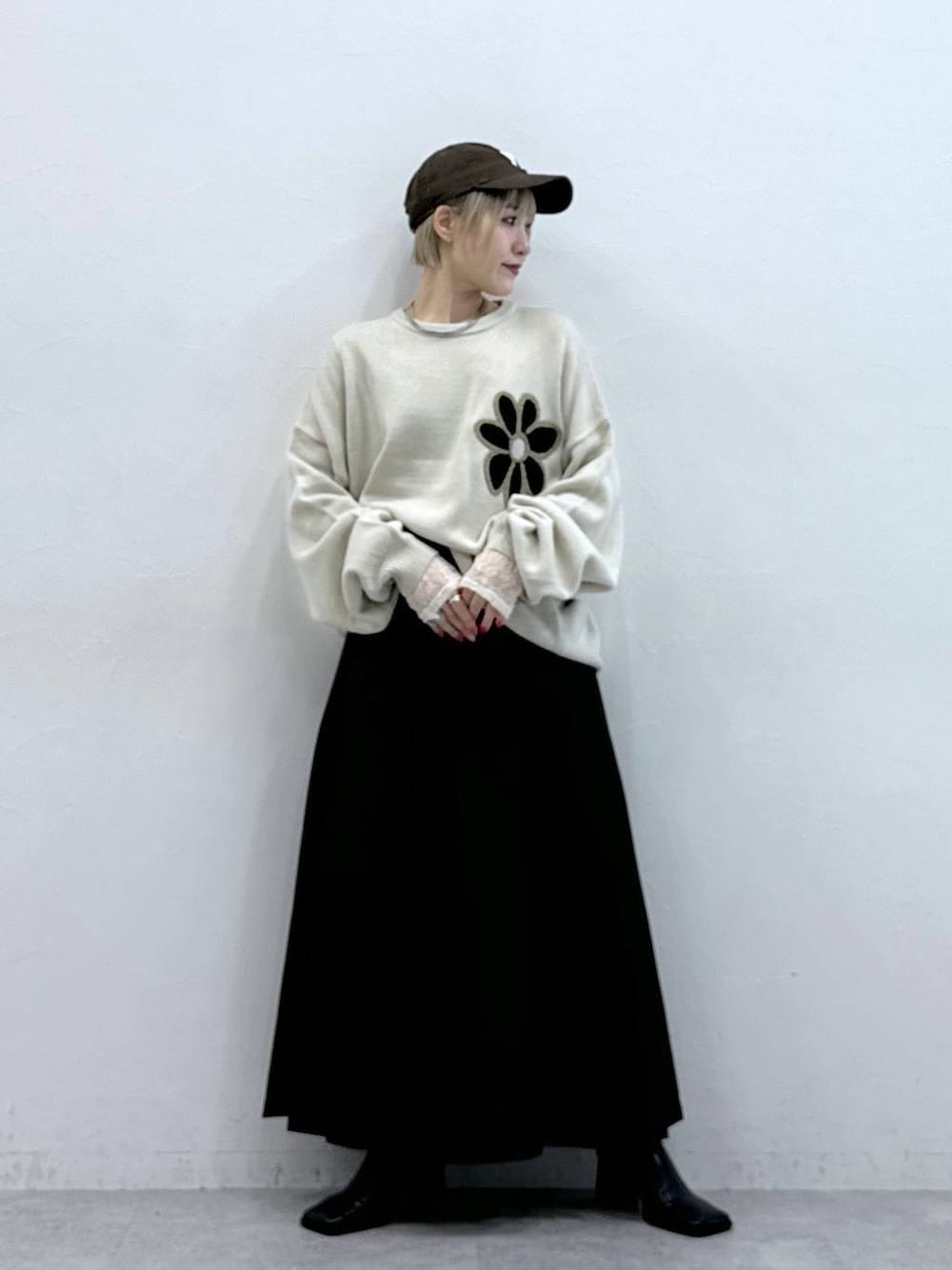 ホワイト系のニット/セーター、ブラウン系のスカート、ホワイト系のTシャツ/カットソーを着用したレディースの秋コーディネートの1枚目の写真