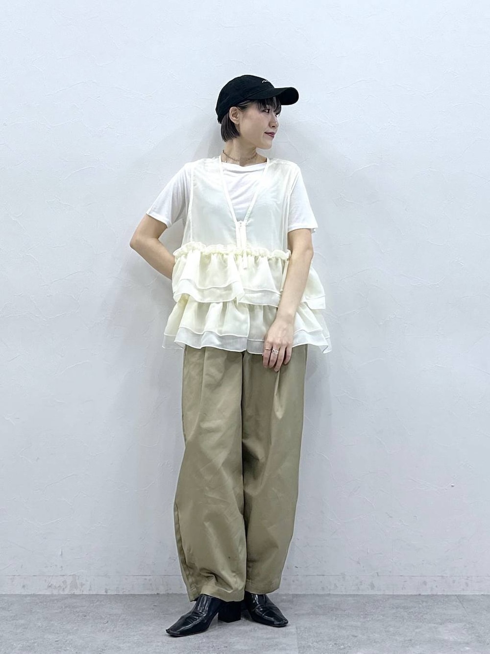 ベージュ系のチノパンツ、ホワイト系のTシャツ/カットソー、ホワイト系のベストを着用したレディースの春コーディネートの1枚目の写真