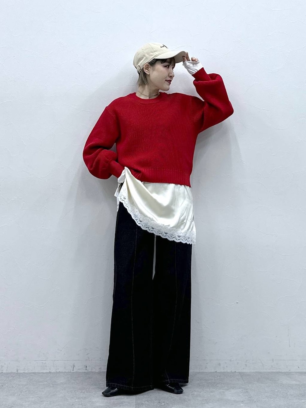 レッド系のニット/セーター、ブラック系のデニムパンツ、ホワイト系のキャミソールを着用したレディースの冬コーディネートの1枚目の写真