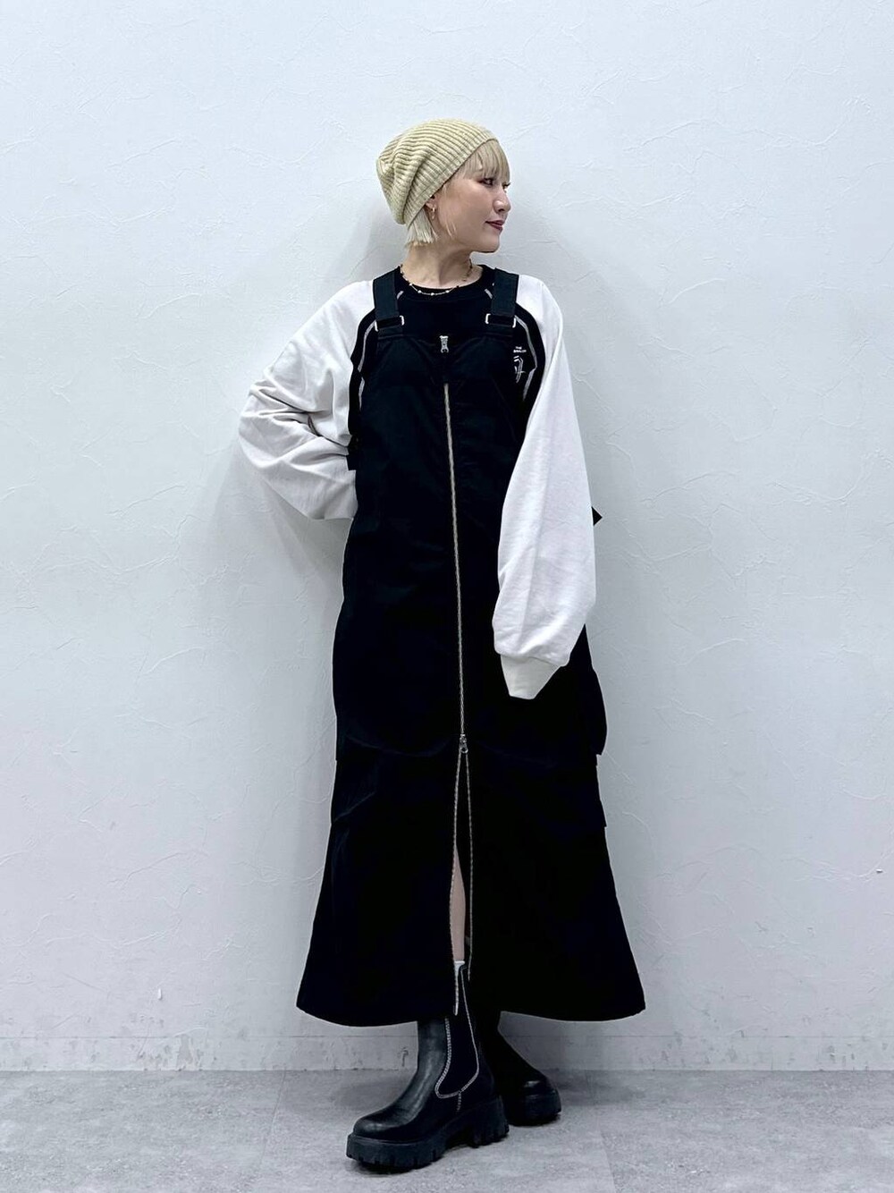 ブラック系のジャンパースカート、ブラック系のスウェット、ベージュ系のハンチング/ベレー帽を着用したレディースの秋コーディネートの1枚目の写真