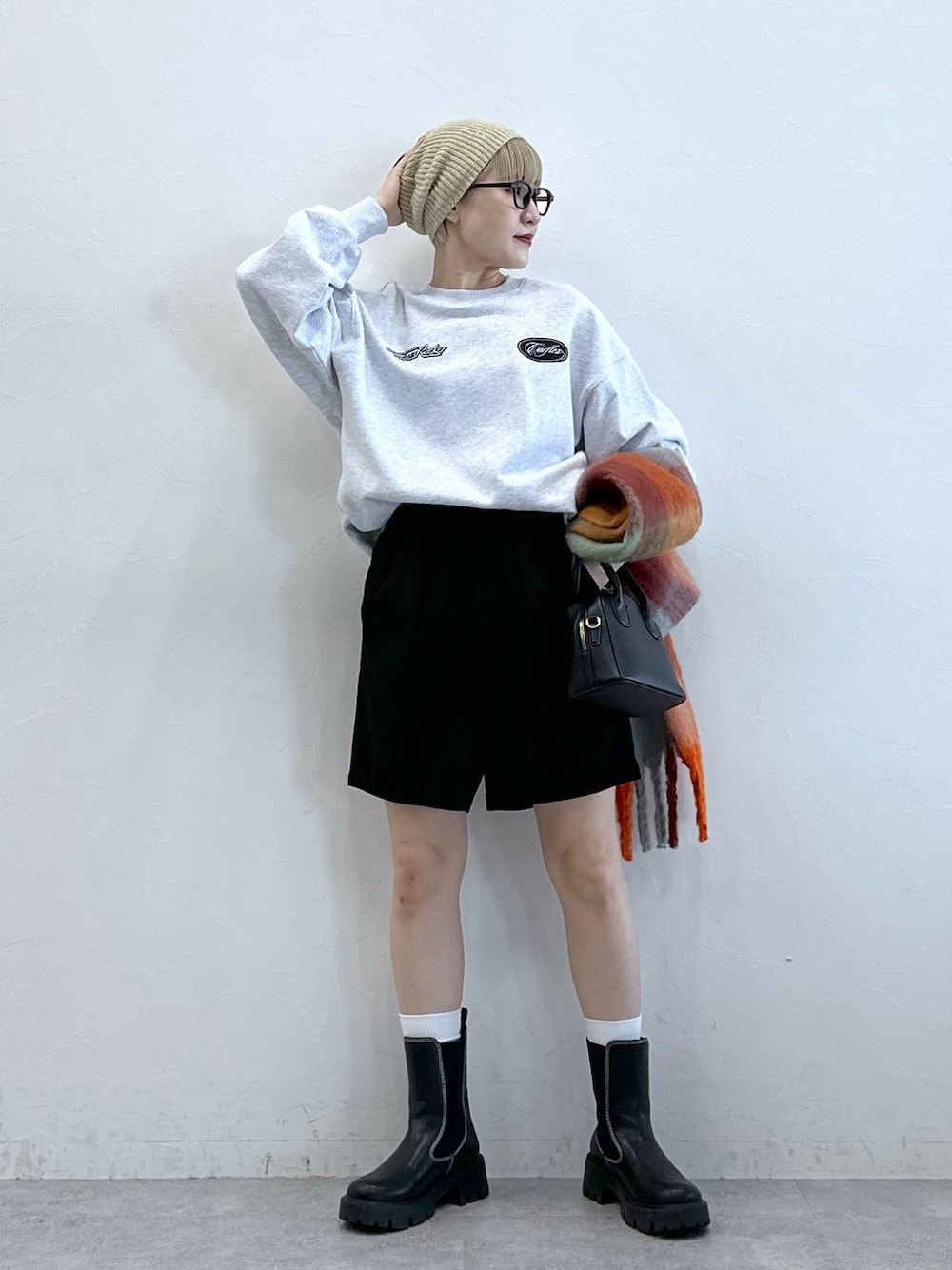 ブラック系のチノパンツ、ブラック系のブーツ、グレー系のスウェットを着用したレディースの冬コーディネートの1枚目の写真