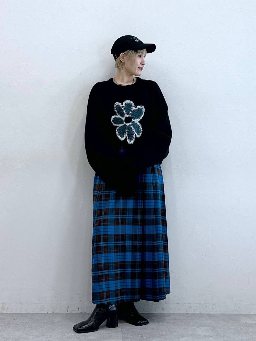 ブラック系のニット/セーター、ブルー系のスカート、ブラック系のキャップを着用したレディースの秋コーディネートの1枚目の写真