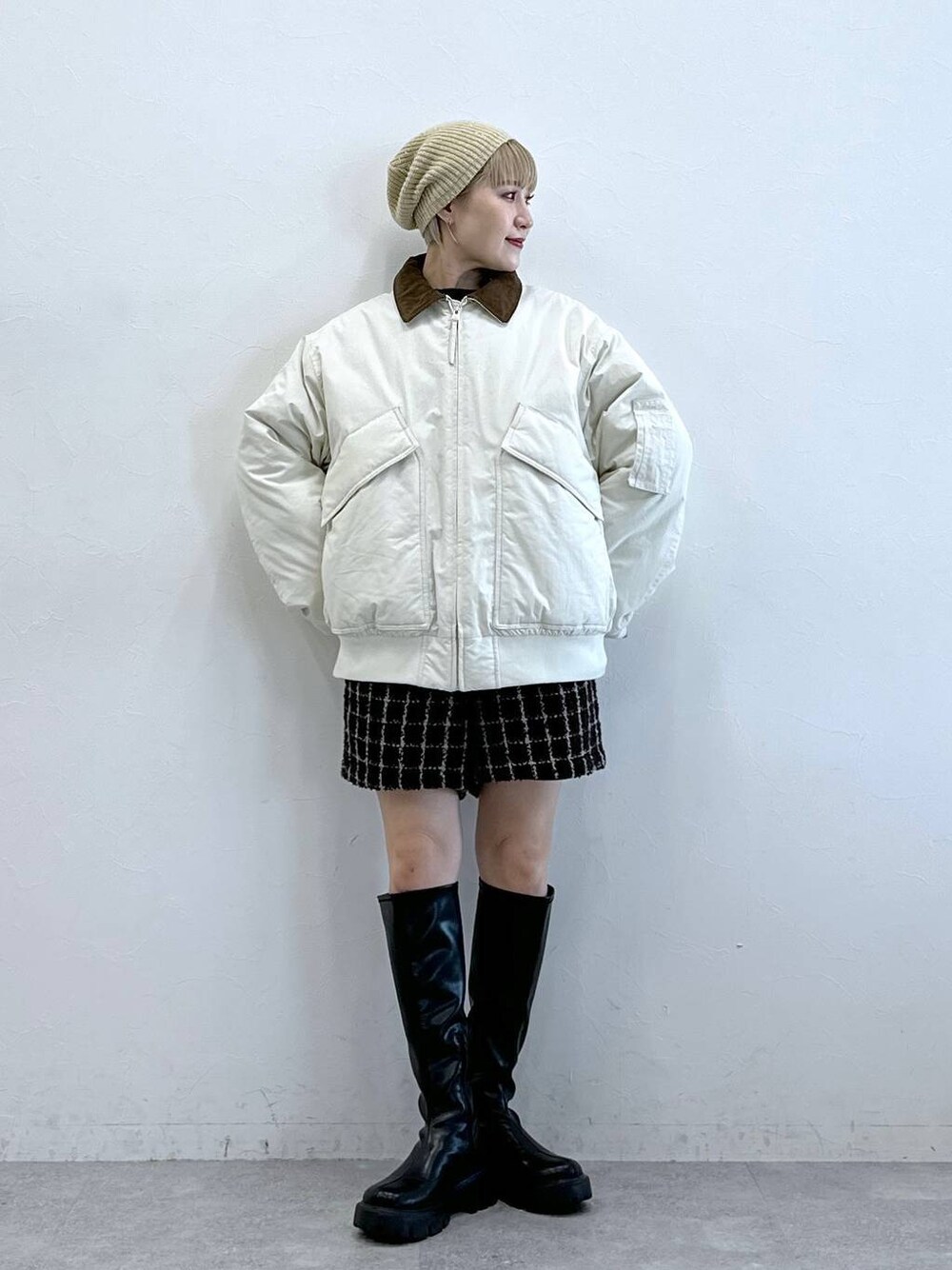 ブラック系のブーツ、ホワイト系のブルゾン、ブラウン系のその他パンツを着用したレディースの冬コーディネートの1枚目の写真