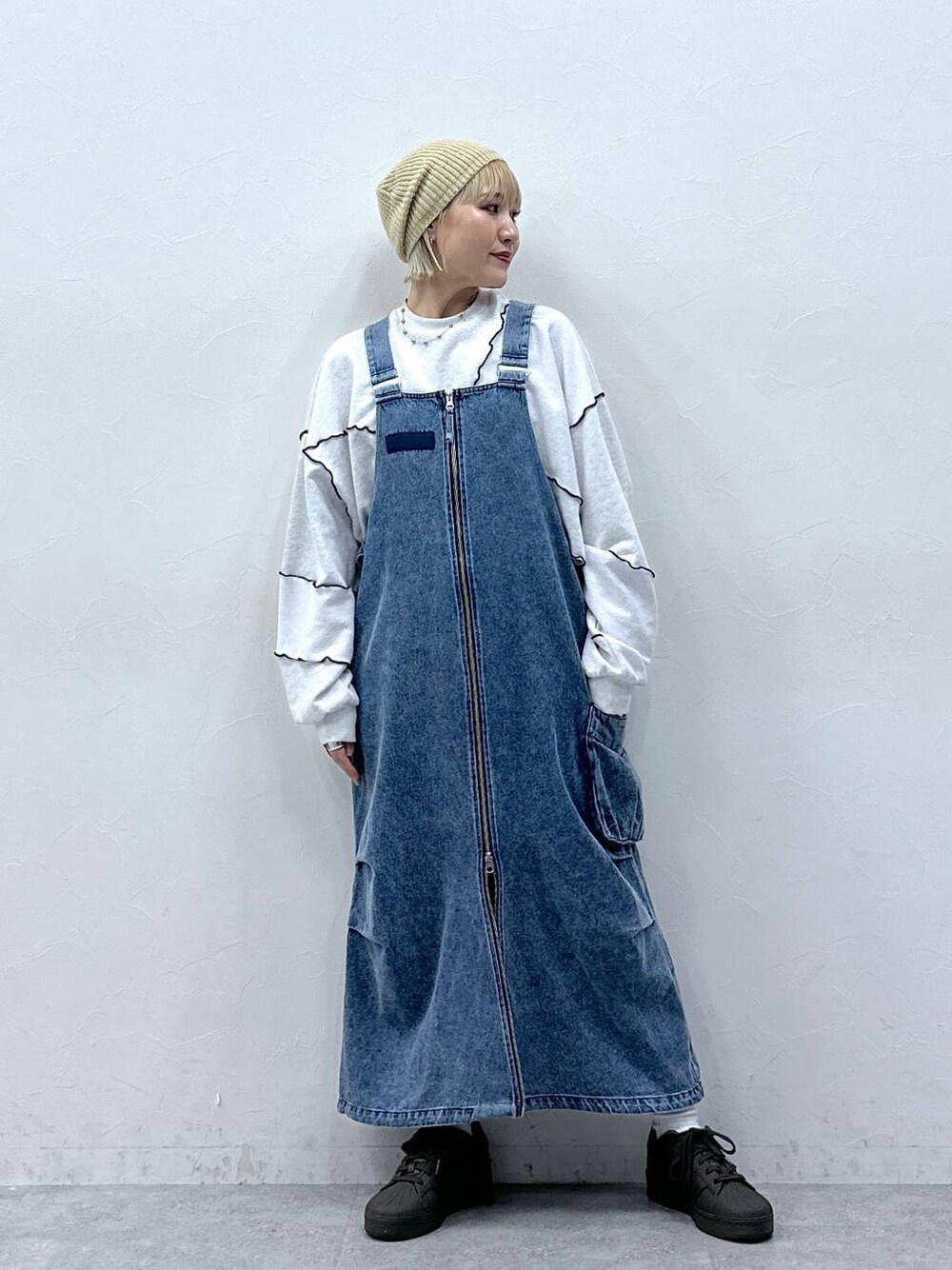ブルー系のジャンパースカート、ホワイト系のスウェット、ベージュ系のハンチング/ベレー帽を着用したレディースの秋コーディネートの1枚目の写真