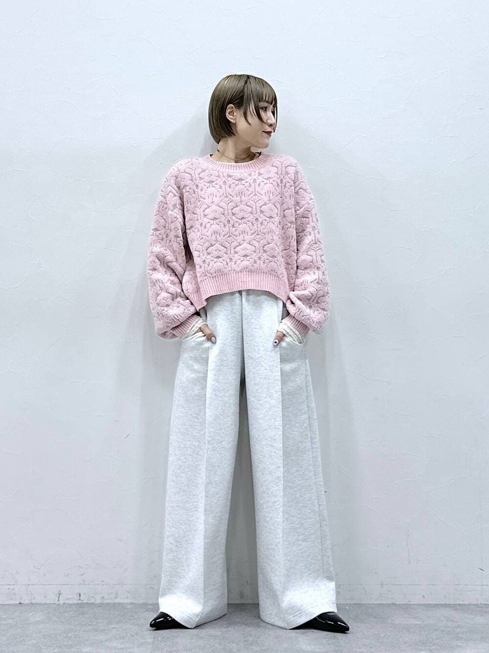 ホワイト系のTシャツ/カットソー、ブラック系のパンプス、ピンク系のニット/セーターを着用したレディースの冬コーディネートの1枚目の写真