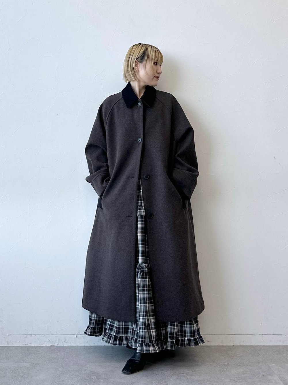 ブラウン系のステンカラーコート、ブラック系のスカートを着用したレディースの冬コーディネートの1枚目の写真