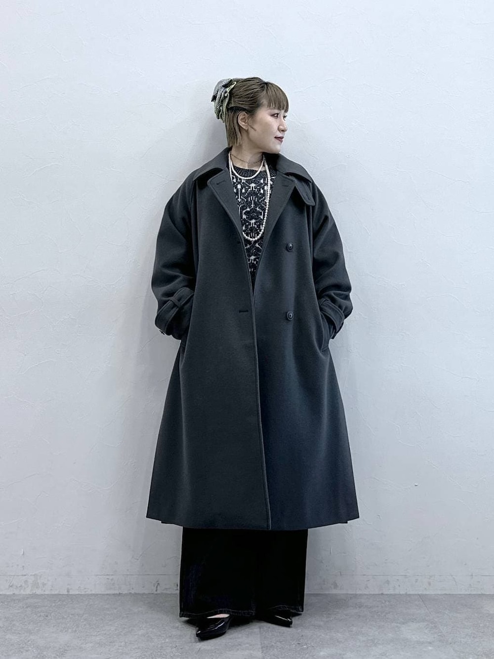 グレー系のステンカラーコート、ブラック系のニット/セーター、ブラック系のパンプスを着用したレディースの冬コーディネートの1枚目の写真