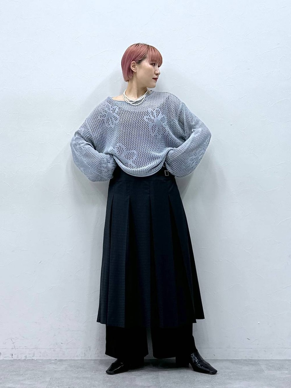 ブラック系のスラックス、ブルー系のニット/セーター、グレー系のスカートを着用したレディースの春コーディネートの1枚目の写真