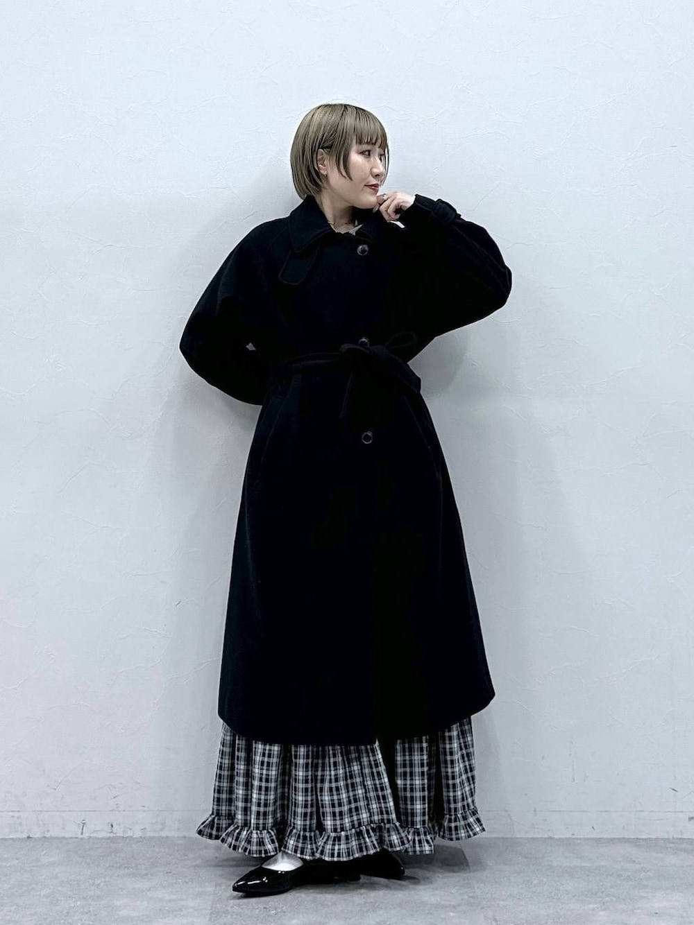 ブラック系のステンカラーコート、ブラック系のスカート、ブラック系のパンプスを着用したレディースの冬コーディネートの1枚目の写真