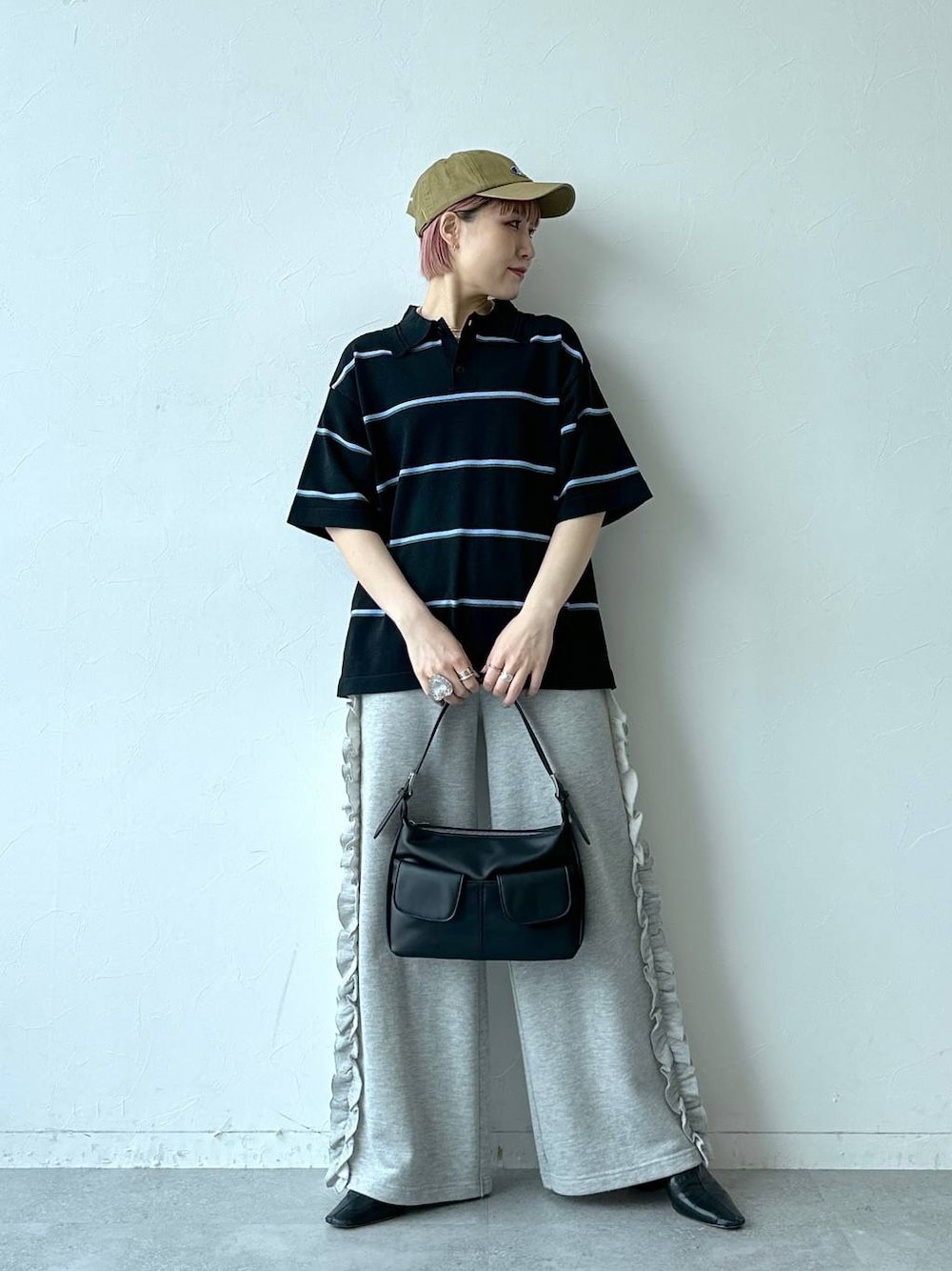 グレー系のスウェットパンツ、ブラック系のポロシャツ、ベージュ系のキャップを着用したレディースの春コーディネートの1枚目の写真