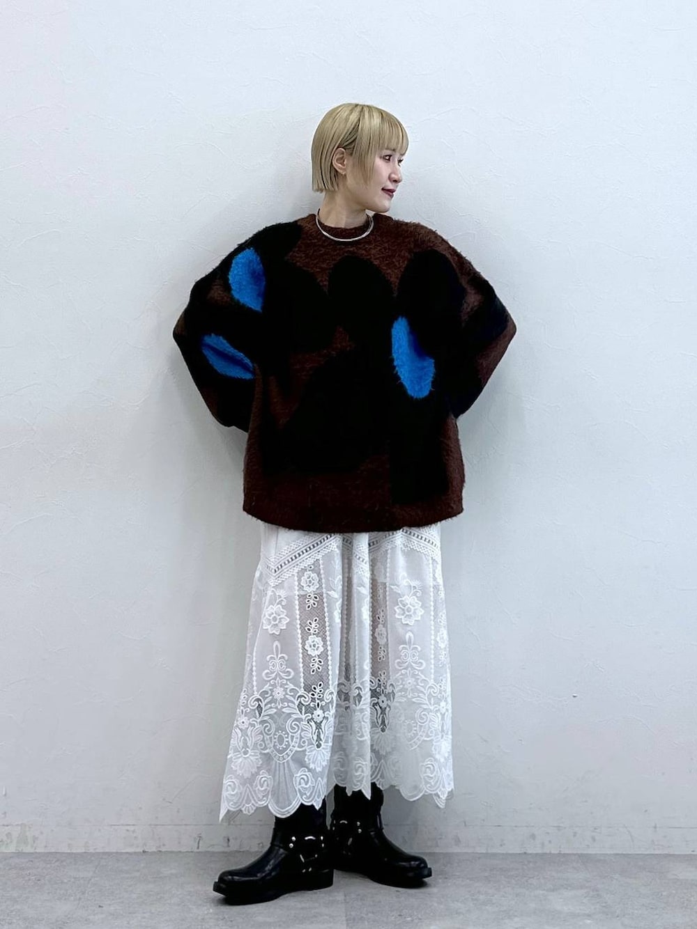 ブラック系のブーツ、ブラウン系のニット/セーター、ホワイト系のスカートを着用したレディースの秋コーディネートの1枚目の写真