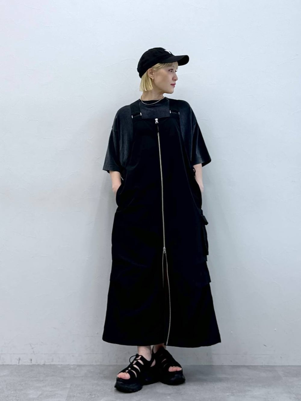 ブラック系のジャンパースカート、ブラック系のサンダル、ブラック系のTシャツ/カットソーを着用したレディースの夏コーディネートの1枚目の写真