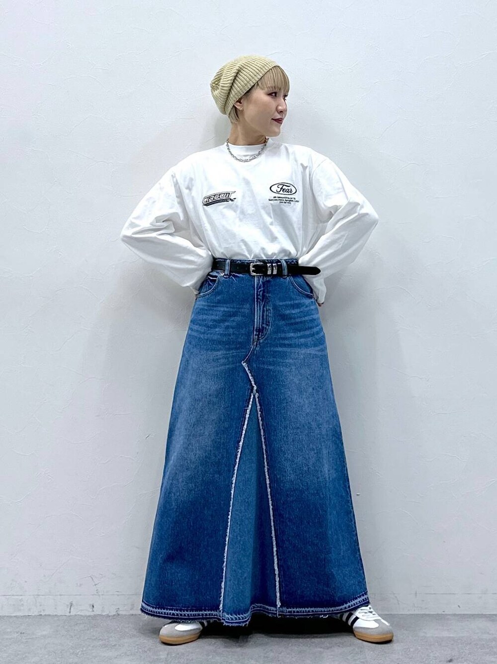 ブルー系のデニムスカート、ホワイト系のTシャツ/カットソー、ベージュ系のハンチング/ベレー帽を着用したレディースの冬コーディネートの1枚目の写真