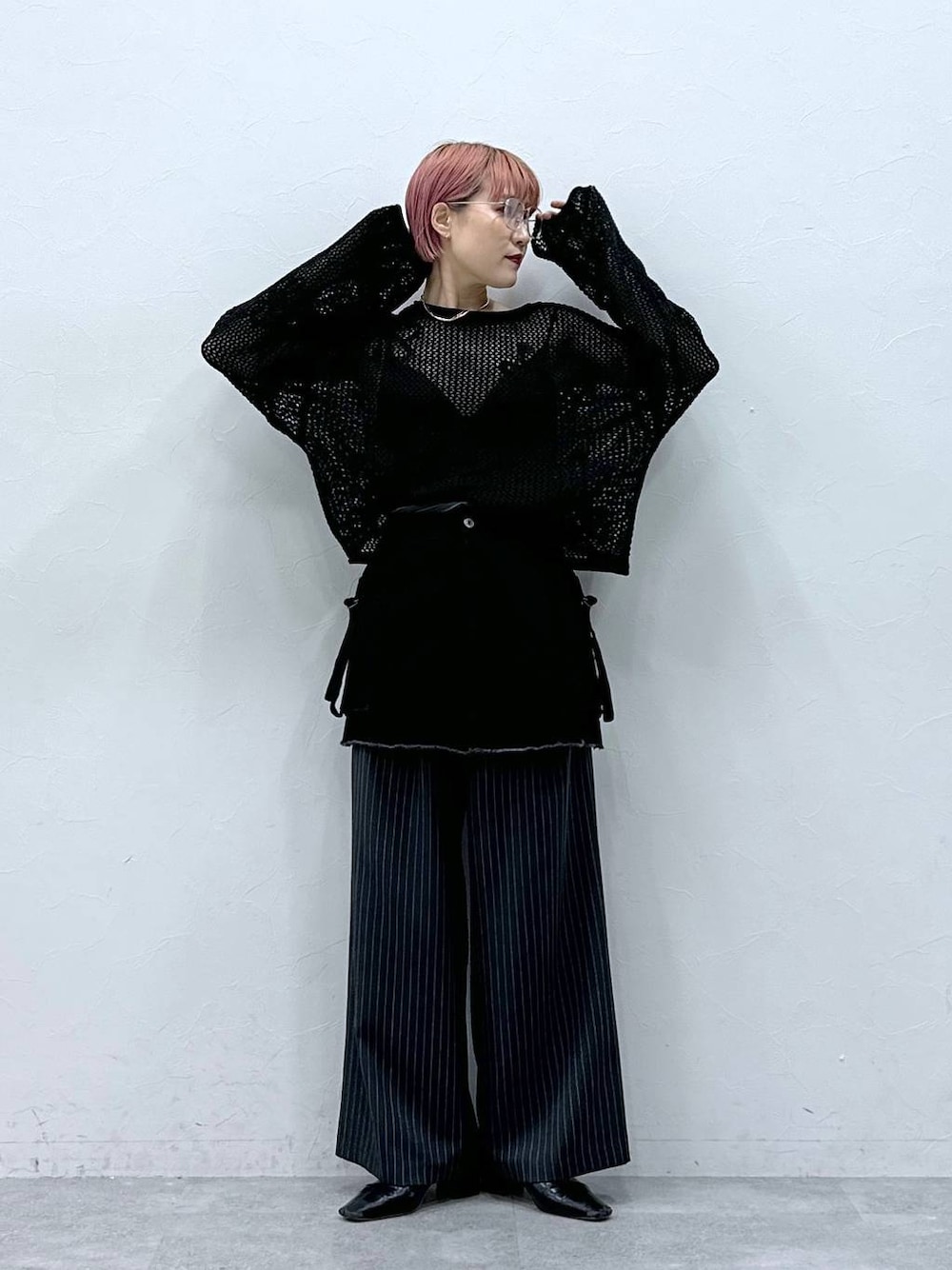 グレー系のスラックス、ブラック系のニット/セーター、ブラック系のスカートを着用したレディースの春コーディネートの1枚目の写真