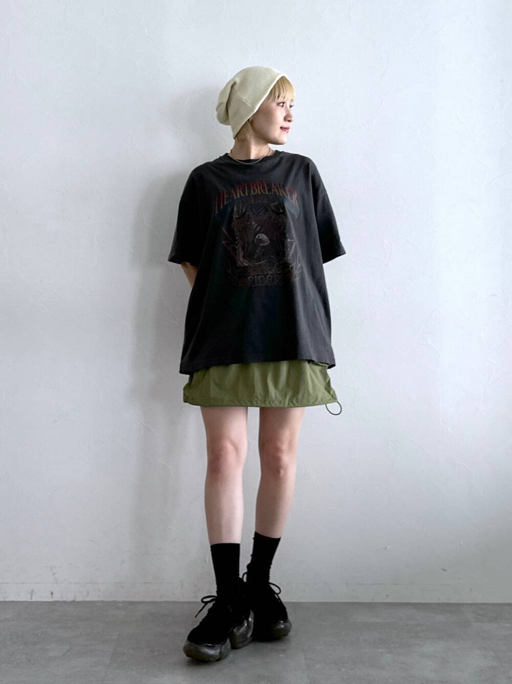 グリーン系のスカート、ブラック系のTシャツ/カットソーを着用したレディースの夏コーディネートの1枚目の写真