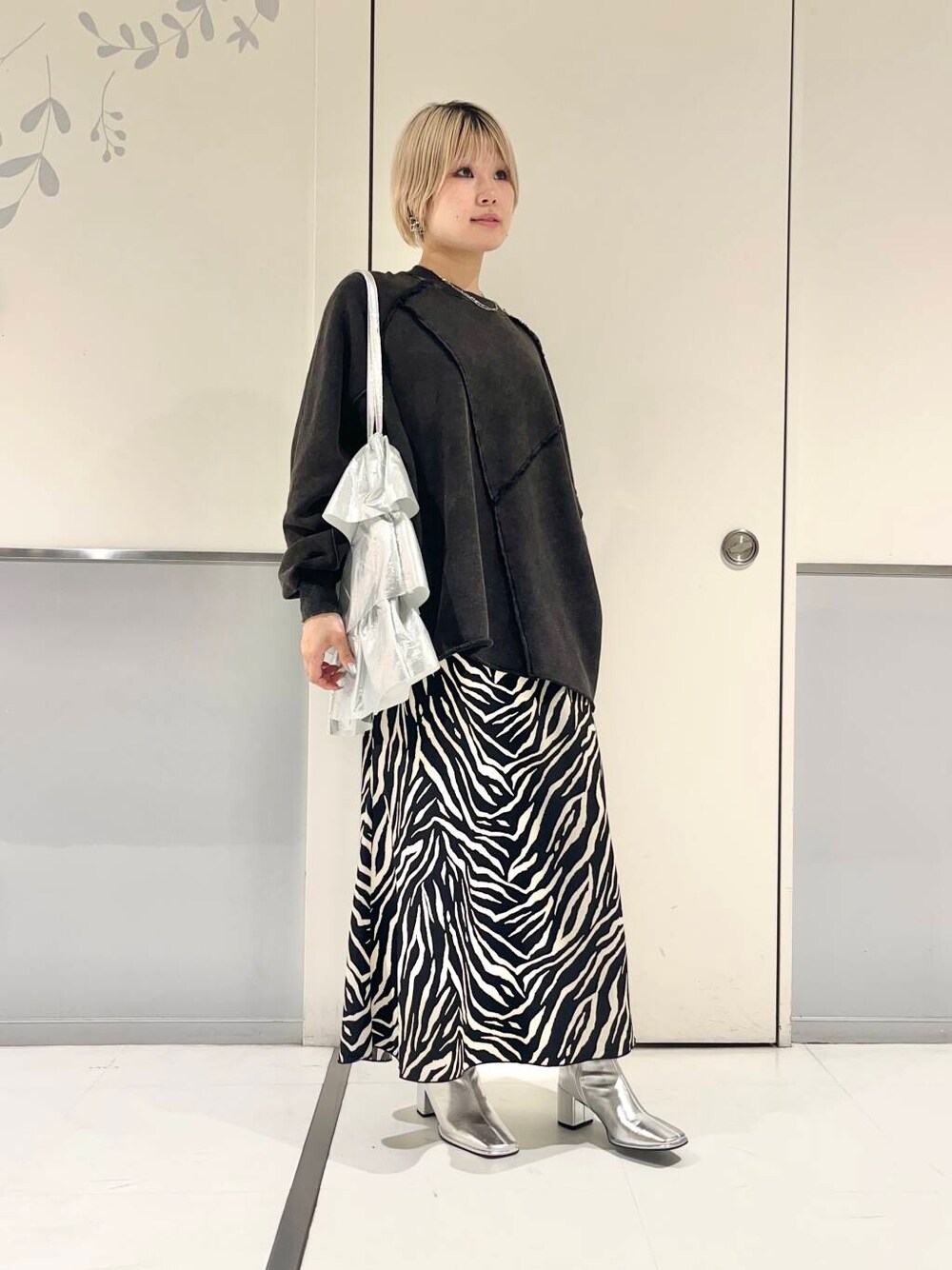 シルバー系のトートバッグ、シルバー系のブーツ、ブラック系のスカートを着用したレディースの秋コーディネートの1枚目の写真