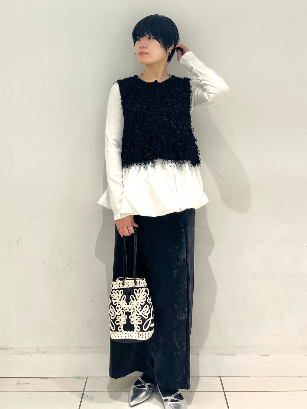 ホワイト系のニット/セーター、ホワイト系のTシャツ/カットソー、ブラック系のスカートを着用したレディースの秋コーディネートの1枚目の写真