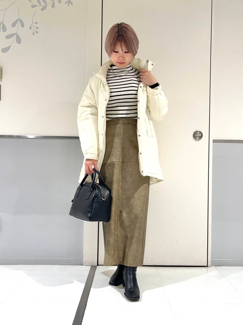 ホワイト系のニット/セーター、ブラック系のボストンバッグ、ブラック系のブーツを着用したレディースの冬コーディネートの1枚目の写真
