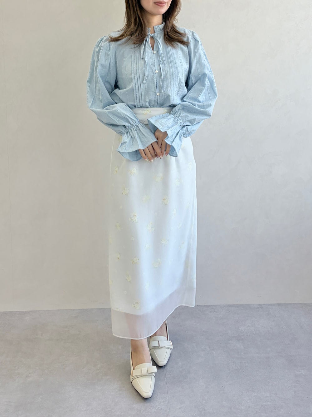 グレー系のスカート、ブルー系のシャツ/ブラウスを着用したレディースの春コーディネートの1枚目の写真