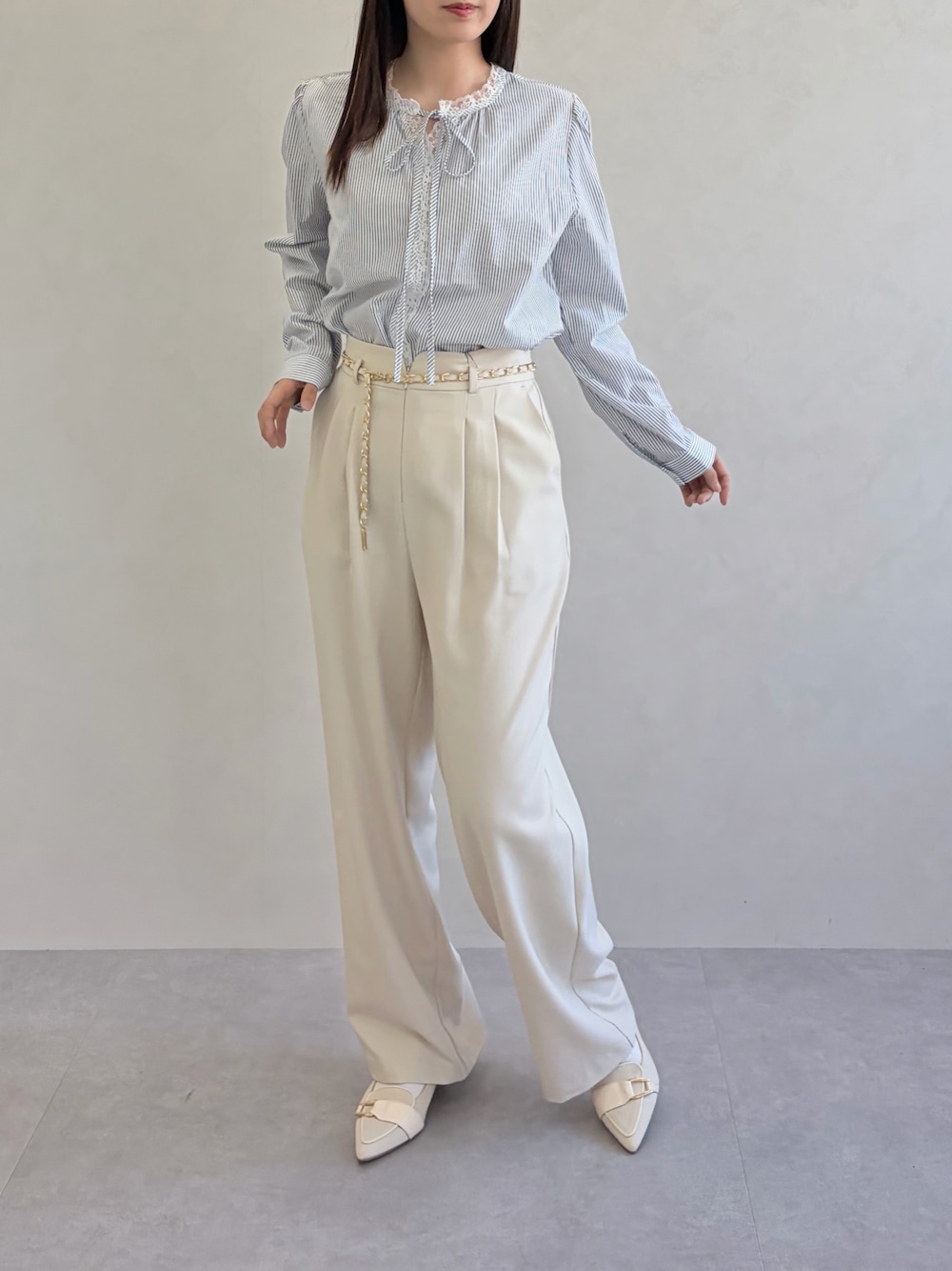 ブルー系のシャツ/ブラウス、ベージュ系のスラックスを着用したレディースの春コーディネートの1枚目の写真