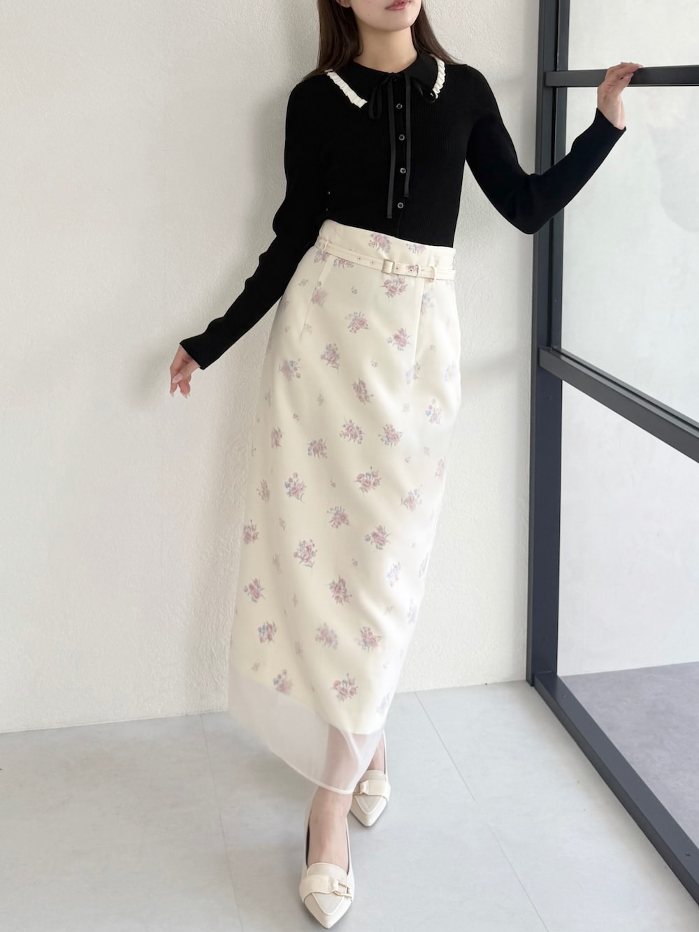 ブラック系のニット/セーター、ベージュ系のシューズ、イエロー系のスカートを着用したレディースの春コーディネートの1枚目の写真