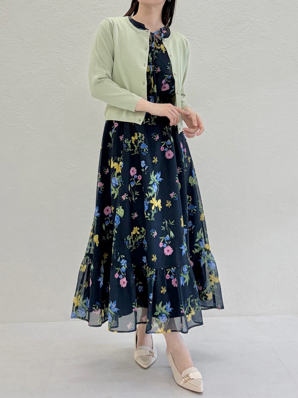 ベージュ系のシューズ、ブルー系のワンピース、グリーン系のカーディガン/ボレロを着用したレディースの春コーディネートの1枚目の写真