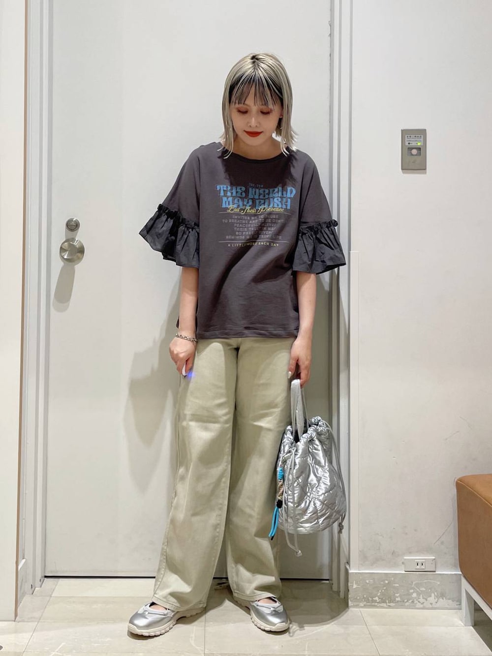 グレー系のスニーカー、ベージュ系のデニムパンツ、シルバー系のハンドバッグを着用したレディースの秋コーディネートの1枚目の写真