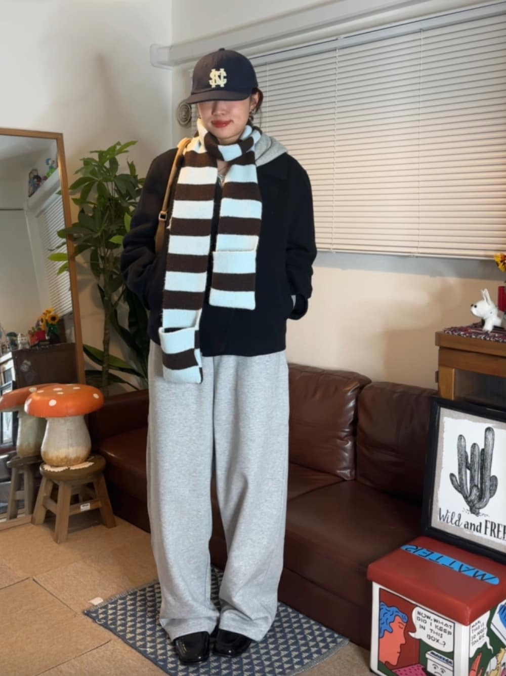 グレー系のスウェットパンツ、ブルー系のピーコート、ブルー系のキャップを着用したレディースの秋コーディネートの1枚目の写真