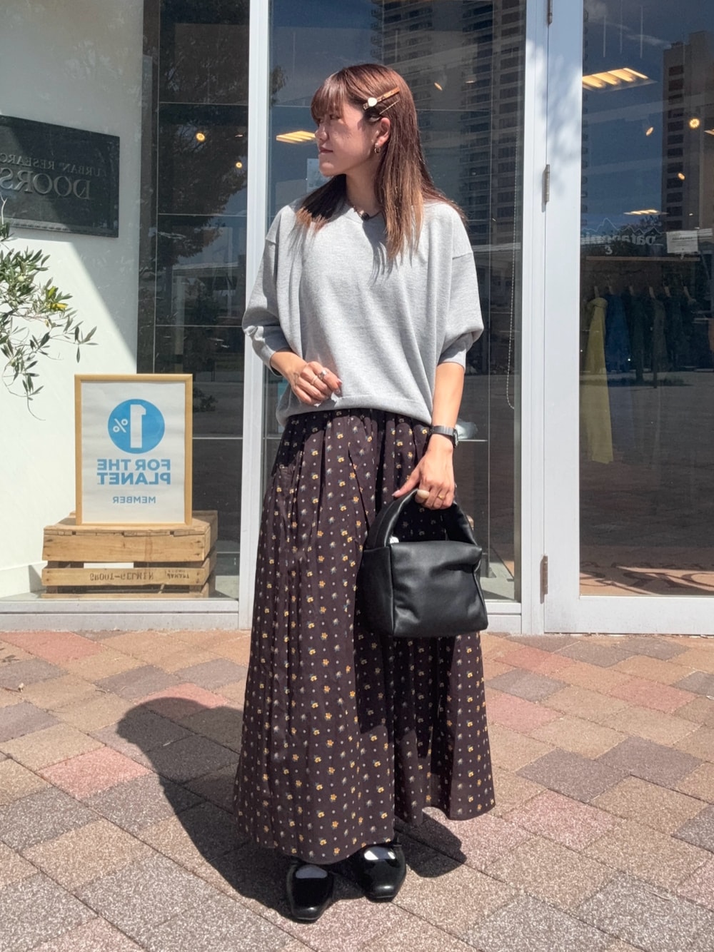 ブラック系のスカート、ブラック系のハンドバッグ、グレー系のニット/セーターを着用したレディースの秋コーディネートの1枚目の写真