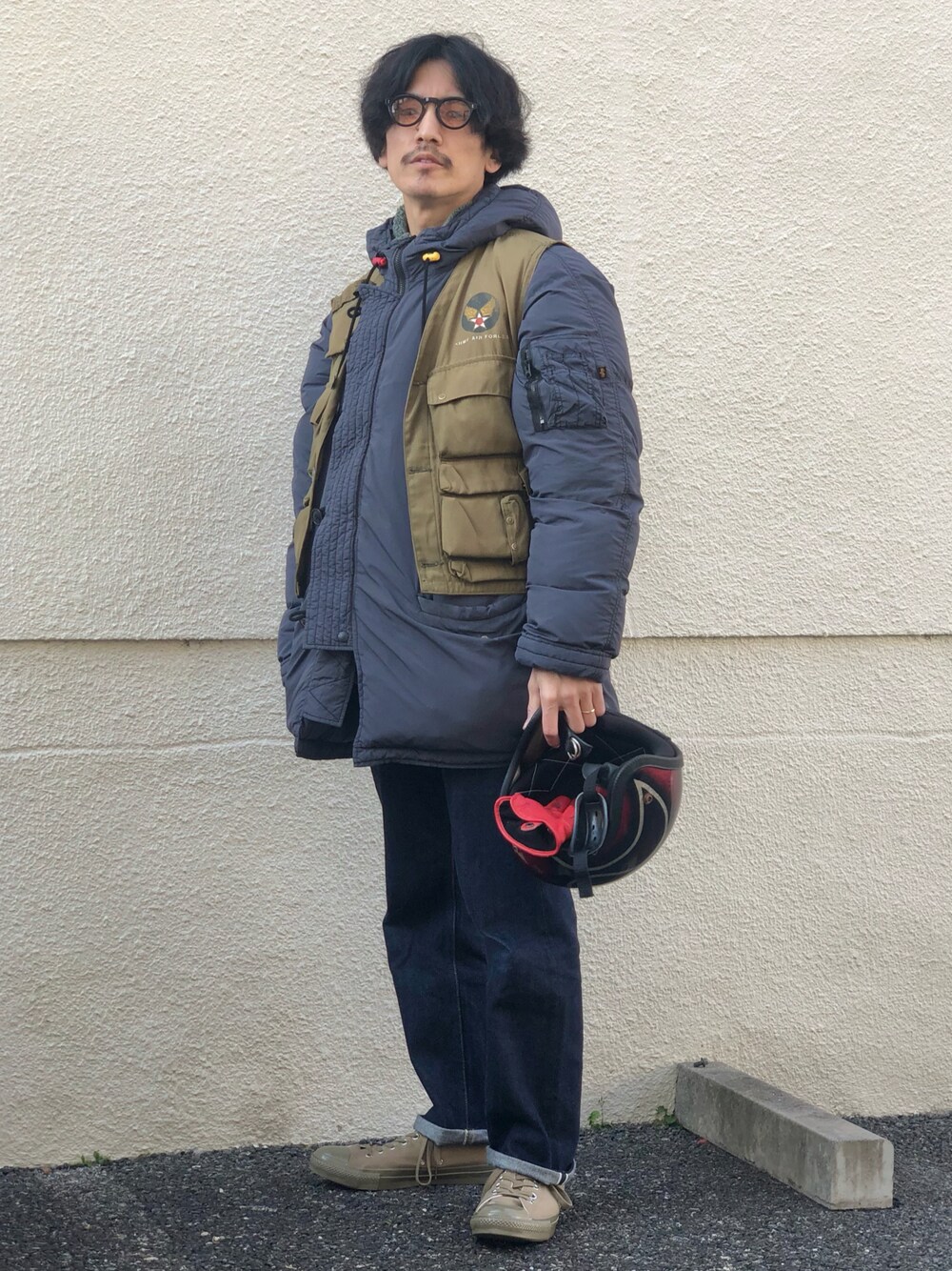 グリーン系のベスト、ブラック系のミリタリージャケット、ブルー系のデニムパンツを着用したメンズの冬コーディネートの1枚目の写真