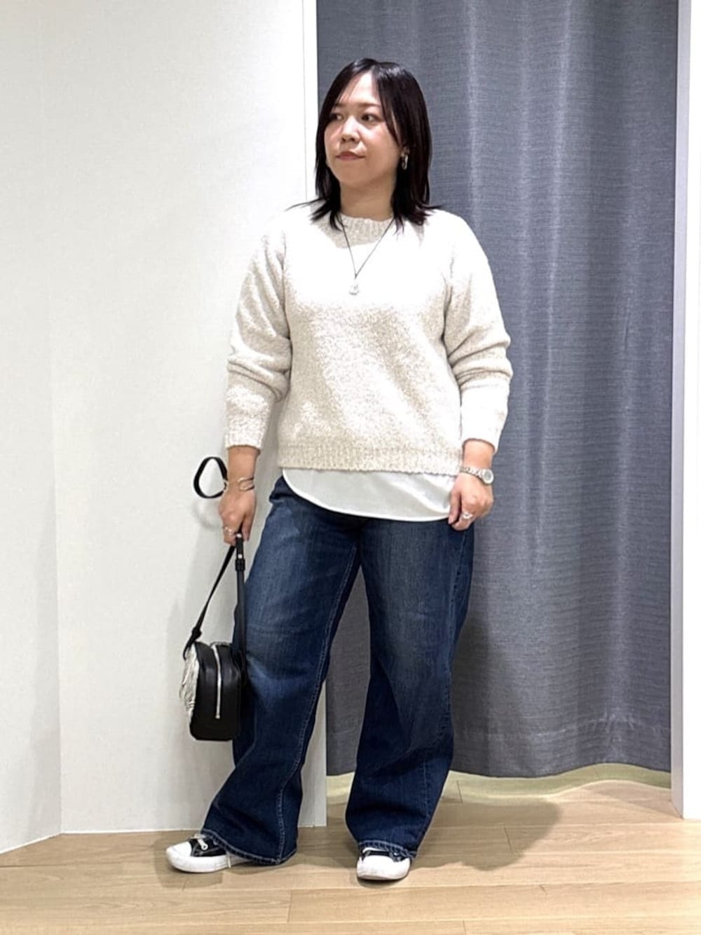 ホワイト系のショルダーバッグ、ホワイト系のニット/セーター、ブルー系のデニムパンツを着用したレディースの冬コーディネートの1枚目の写真