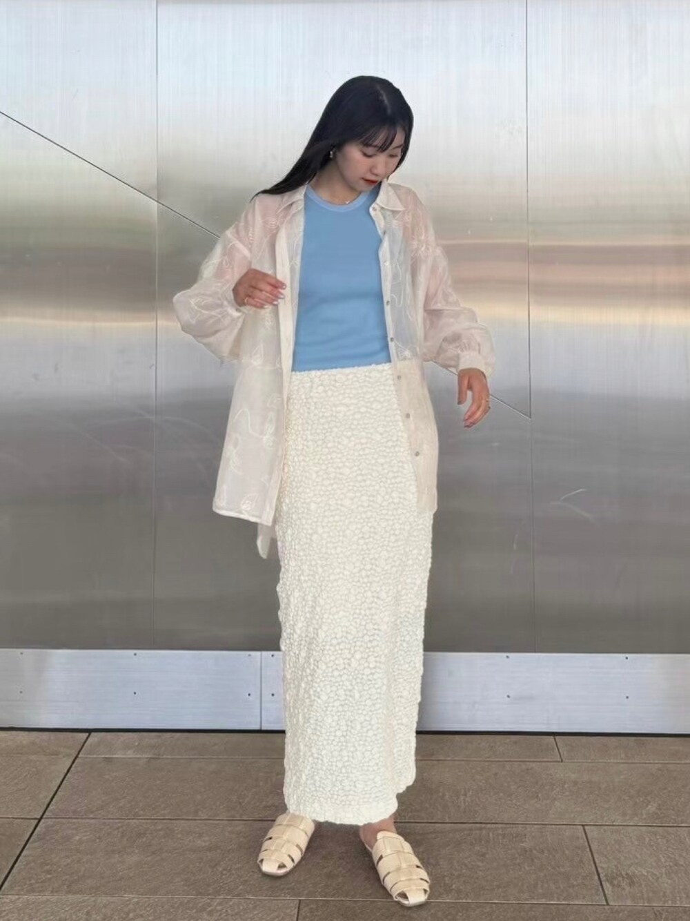 グレー系のタンクトップ、ホワイト系のスカート、ホワイト系のサンダルを着用したレディースの夏コーディネートの1枚目の写真