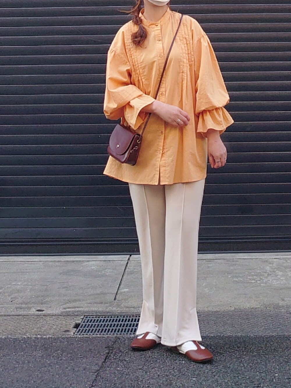 オレンジ系のシャツ/ブラウス、ブラック系のベスト、ベージュ系のスラックスを着用したレディースの冬コーディネートの2枚目の写真