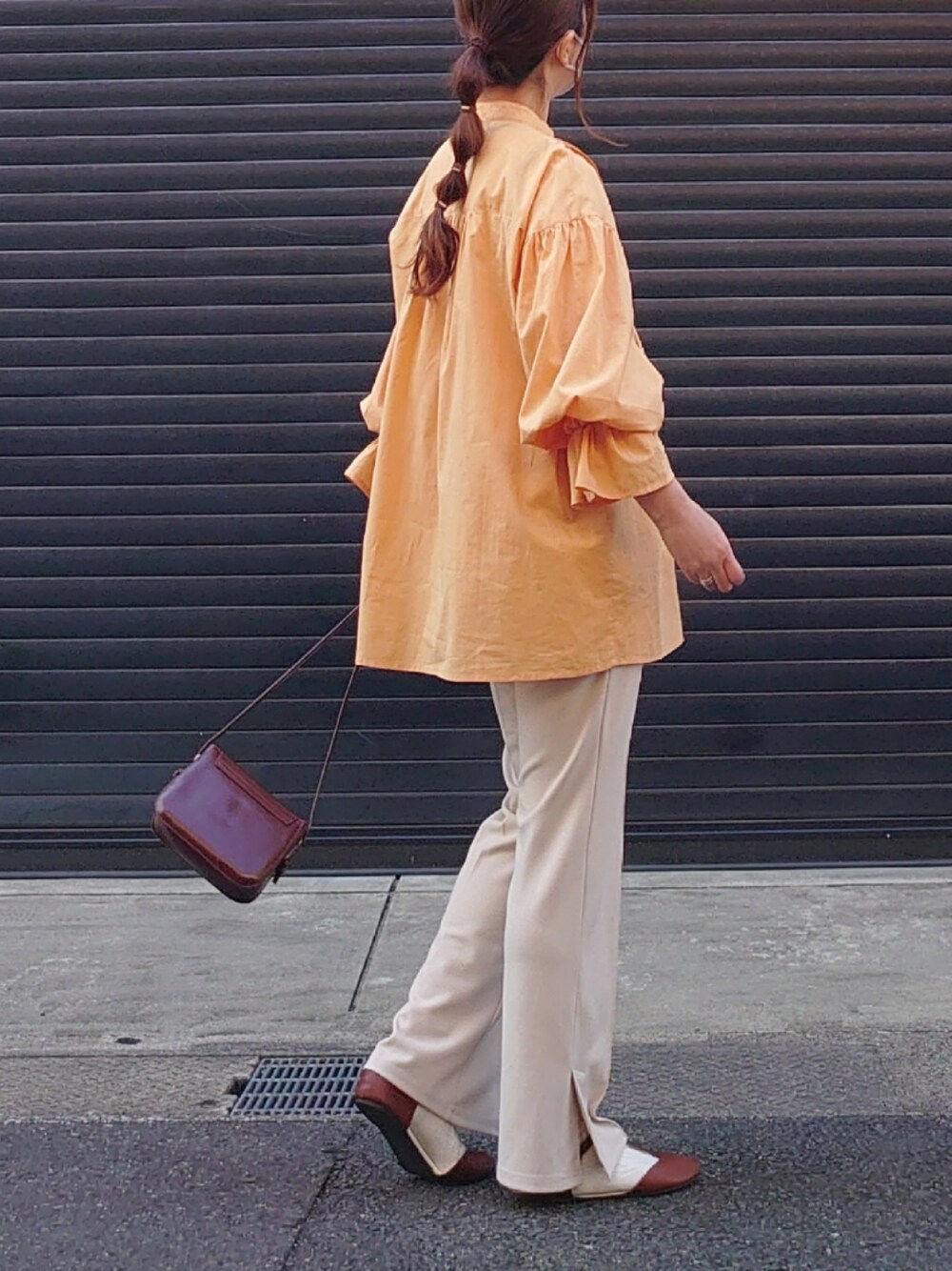 オレンジ系のシャツ/ブラウス、ブラック系のベスト、ベージュ系のスラックスを着用したレディースの冬コーディネートの4枚目の写真