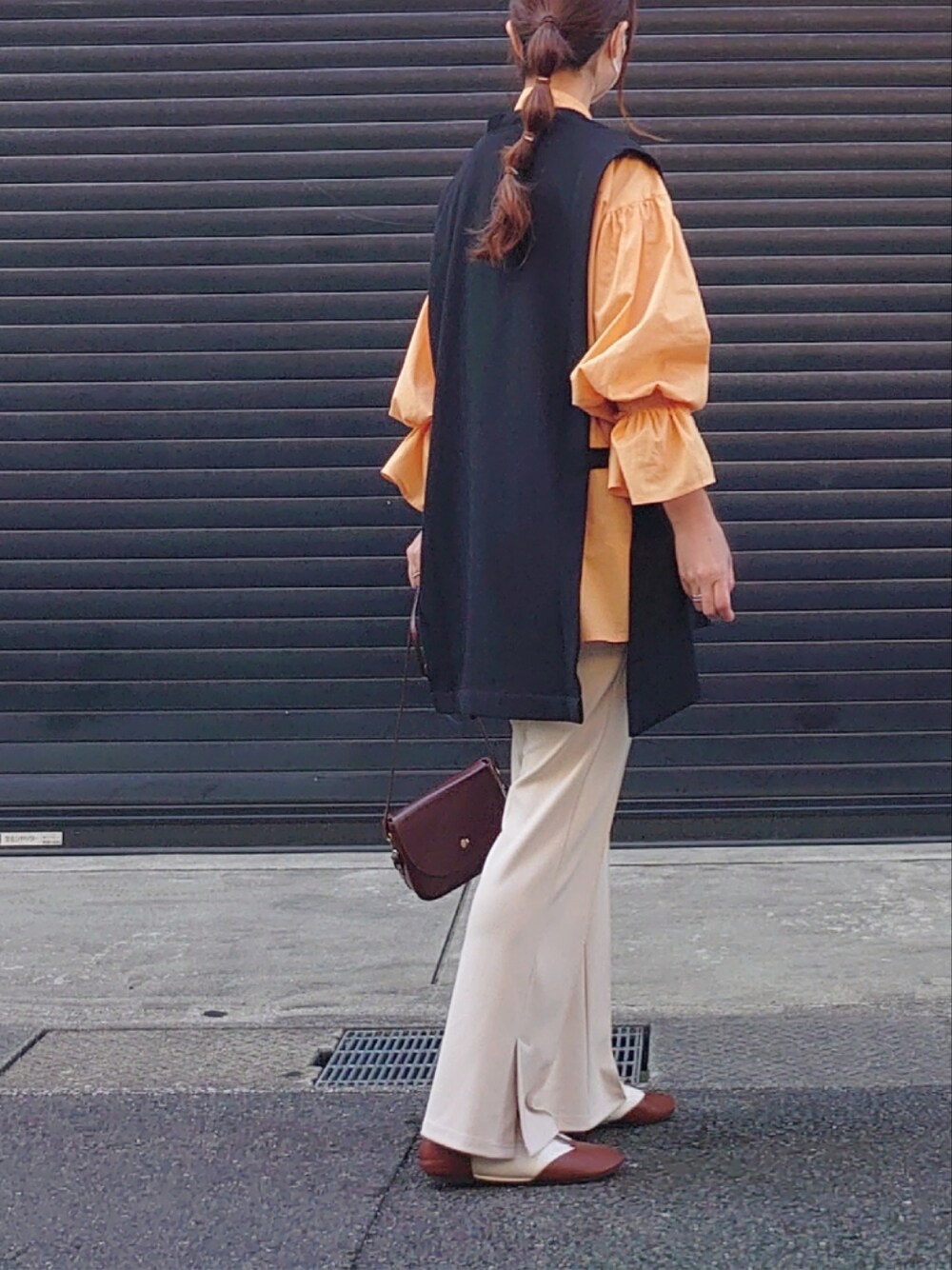 オレンジ系のシャツ/ブラウス、ブラック系のベスト、ベージュ系のスラックスを着用したレディースの冬コーディネートの3枚目の写真