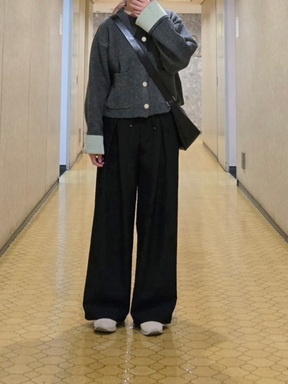 グレー系のカーディガン/ボレロ、ブラック系のスラックス、ホワイト系のブルゾンを着用したレディースの秋コーディネートの1枚目の写真