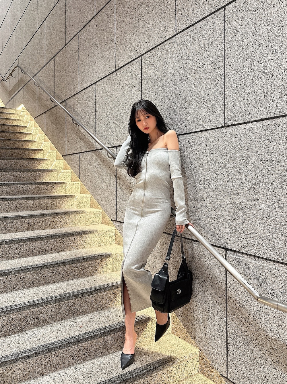 グレー系のワンピース、ブラック系のハンドバッグを着用したレディースの秋コーディネートの1枚目の写真