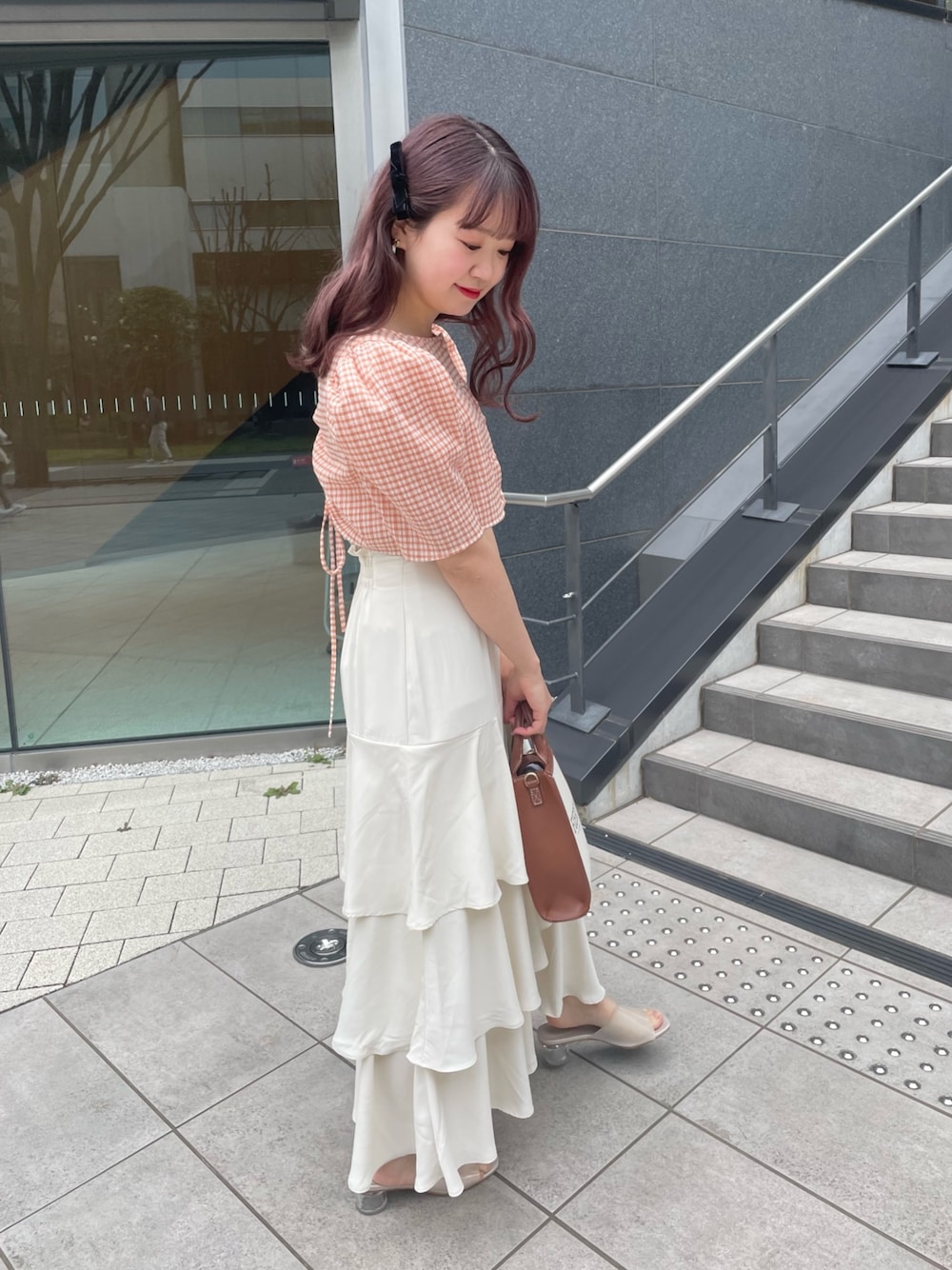 イエロー系のショルダーバッグ、オレンジ系のワンピース、ホワイト系のスカートを着用したレディースの春コーディネートの4枚目の写真