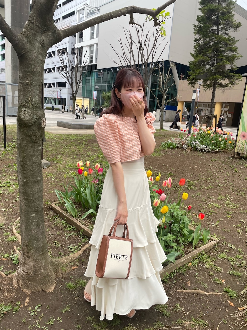 イエロー系のショルダーバッグ、オレンジ系のワンピース、ホワイト系のスカートを着用したレディースの春コーディネートの2枚目の写真