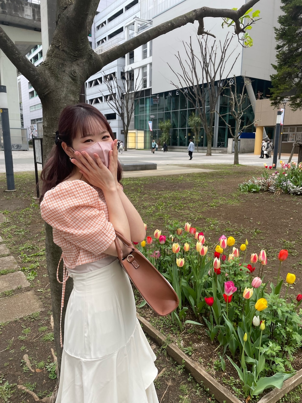 イエロー系のショルダーバッグ、オレンジ系のワンピース、ホワイト系のスカートを着用したレディースの春コーディネートの3枚目の写真