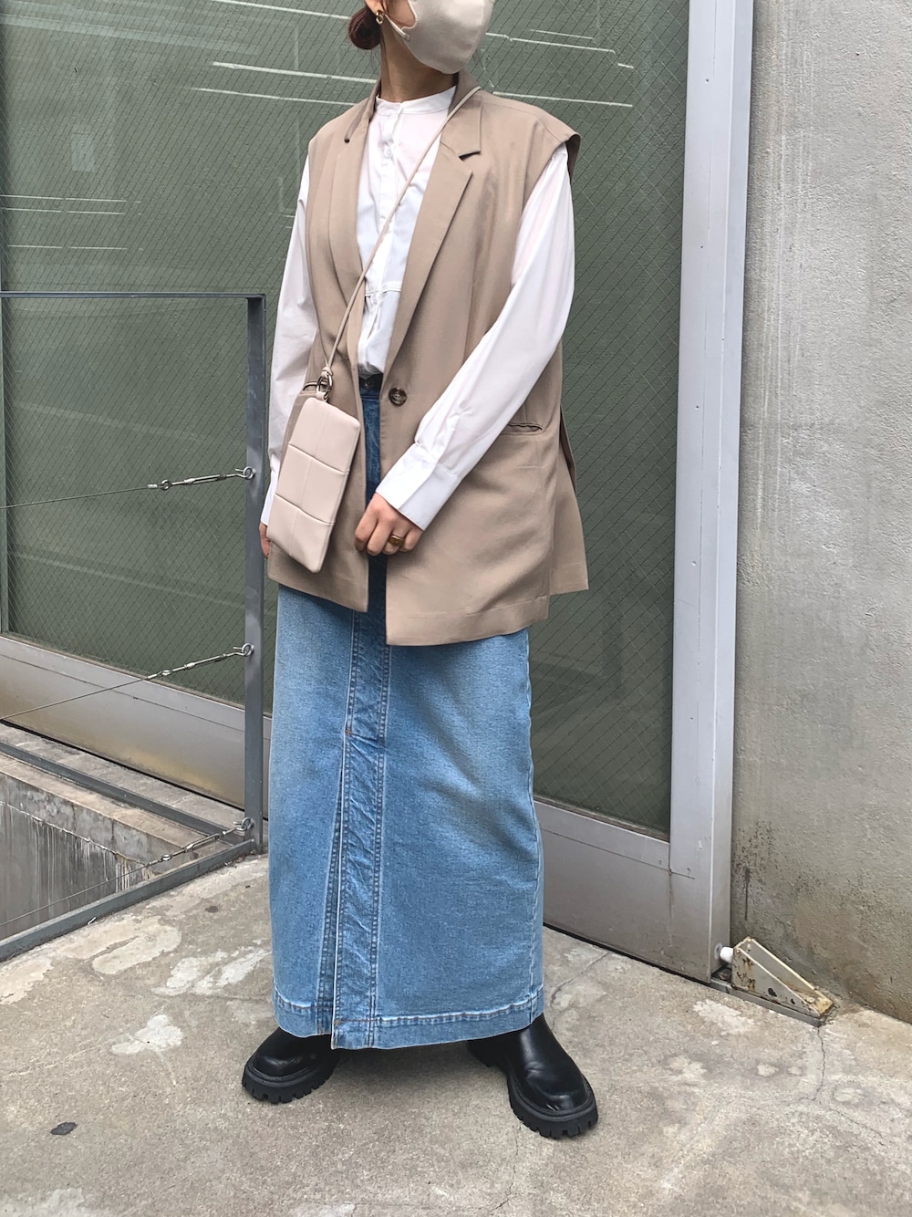 ブラック系のベスト、ホワイト系のシャツ/ブラウス、ブルー系のデニムスカートを着用したレディースの冬コーディネートの1枚目の写真