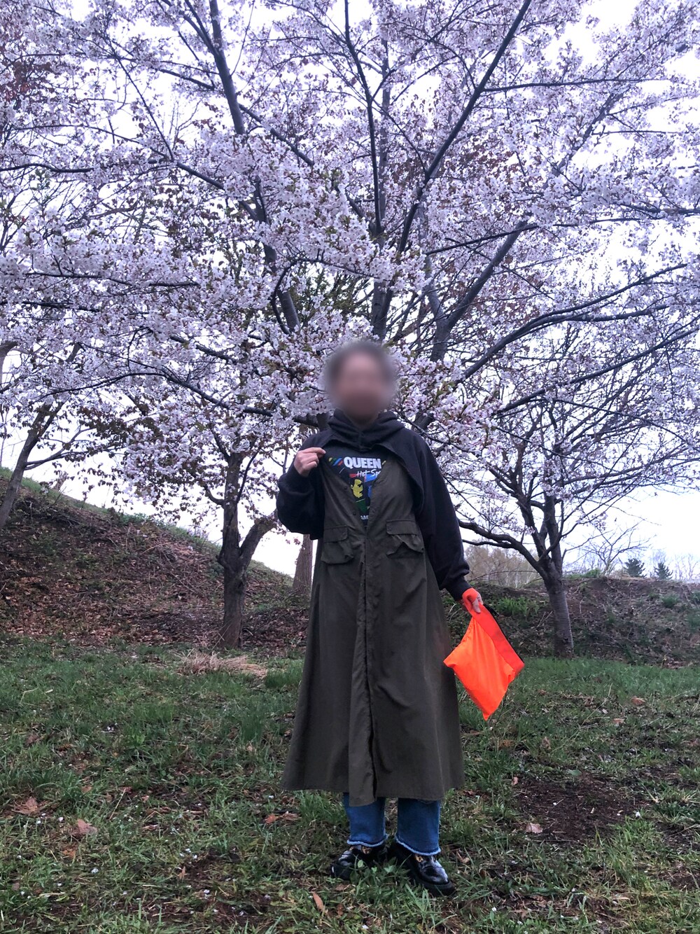 オレンジ系のトートバッグ、ブルー系のデニムパンツ、ブラック系のシューズを着用したレディースの春コーディネートの1枚目の写真